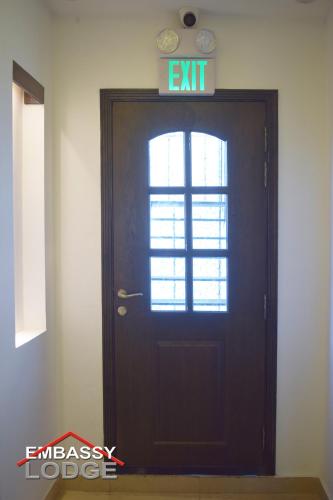 a black door with an exit sign above it at Embassy Lodge in Islamabad