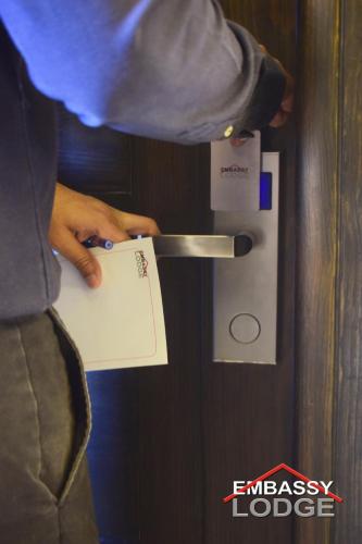 a person holding a piece of paper on a door at Embassy Lodge in Islamabad