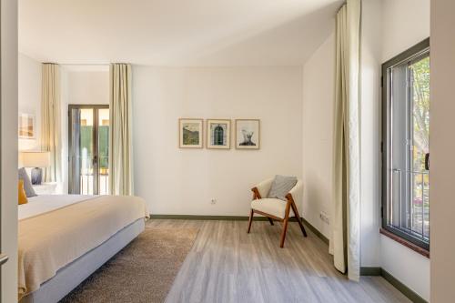 Fort Bay Suite Apartments في ماتشيكو: غرفة نوم بسرير وكرسي ونافذة