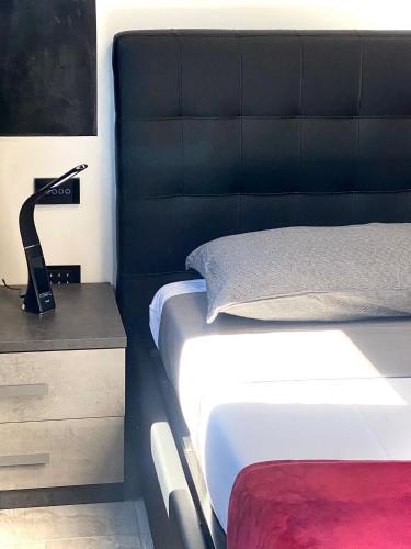 a bed with a black headboard and a lamp on a night stand at HOTEL TECH in Brembate