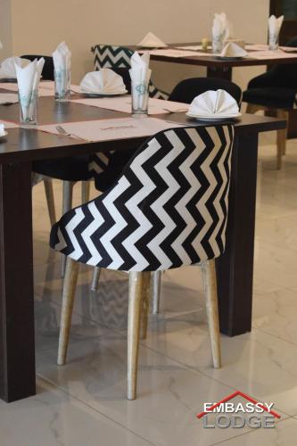 a wooden table with a black and white rug on a chair at Embassy Lodge in Islamabad