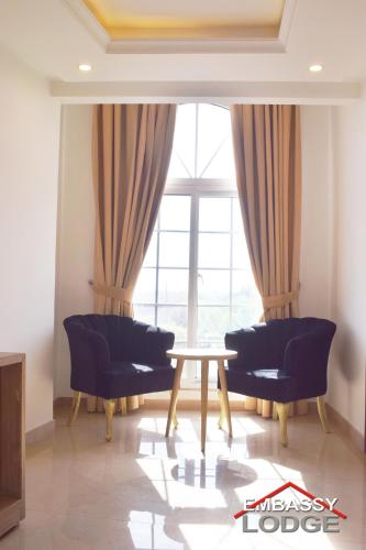 a living room with a table and chairs and a window at Embassy Lodge in Islamabad