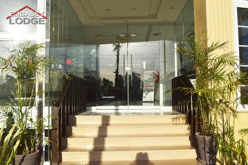 a lobby of a building with stairs and plants at Embassy Lodge in Islamabad