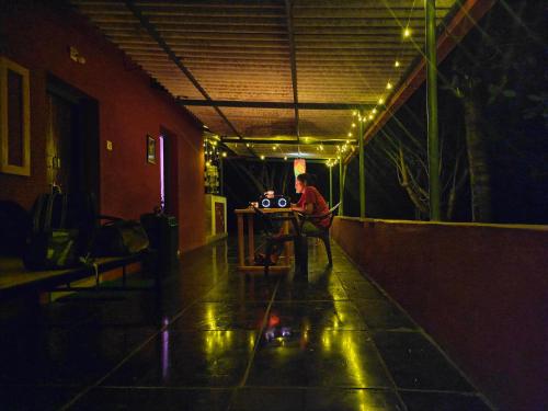 a man sitting at a table in a dark room at Farmhouse with Pool - Kalavady Farmstay in Baindūru