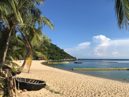 a sandy beach with palm trees and the ocean at Monkeyland Cham island Homestay in Tân Hiệp