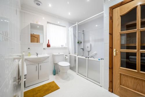 a white bathroom with a toilet sink and a shower at The Pink Bungalow in Dingwall