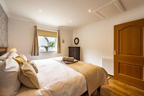 Un dormitorio con una gran cama blanca y una ventana en The Pink Bungalow en Dingwall