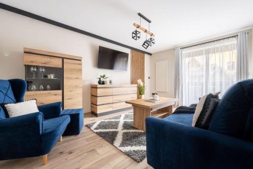 ein Wohnzimmer mit 2 blauen Stühlen und einem Tisch in der Unterkunft Apartamenty Rodzinne ApartZakop in Zakopane