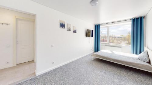 ein weißes Zimmer mit einem Bett und einem Fenster in der Unterkunft Kivi Apartments in Jõhvi