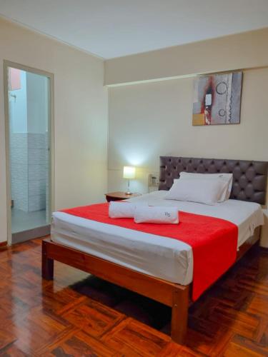 a bedroom with a large bed with a red blanket at Hostal Solari in Trujillo