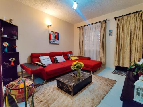 a living room with a red couch and a table at Modern & Comfy Mt. Kenya Sunset View Apartment in Kangaru