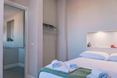 a white bedroom with towels on a bed at Up25 in Naples