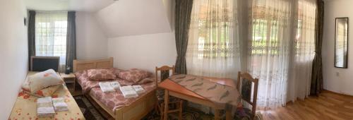 Habitación con 2 camas, escritorio y ventanas. en Casa Viorica și Luis, en Câmpulung Moldovenesc