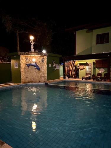 a swimming pool at night with a statue of a dolphin at Recanto Verde Praia Hotel Juquehy in Juquei