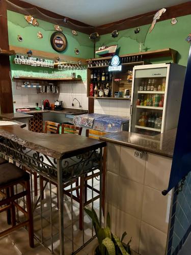 a kitchen with a counter and a bar with tables at Recanto Verde Praia Hotel Juquehy in Juquei