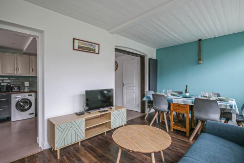 Il comprend un salon doté d'une télévision et d'une table avec des chaises. dans l'établissement Appartement au cœur d'Etretat avec parking gratuit, à Étretat