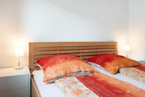 2 bedden met rode en oranje kussens in een slaapkamer bij Ferienwohnung Maier in Bodman-Ludwigshafen