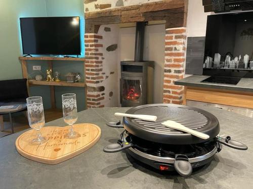 a grill sitting on top of a table with wine glasses at Maison de village avec vue 4/5 personnes Lou Rouchou in Voutezac