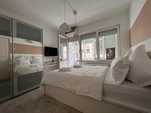 - une chambre avec un grand lit blanc et des fenêtres dans l'établissement Pearl Center - 2BDR, à Bucarest