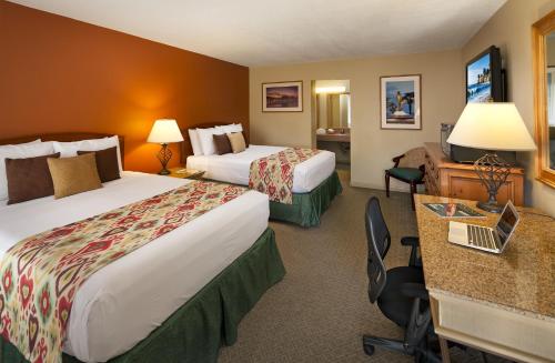 a hotel room with two beds and a desk at Sandpiper Lodge - Santa Barbara in Santa Barbara