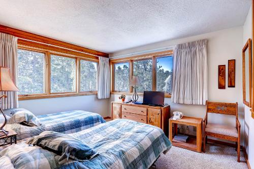 a bedroom with two beds and a desk and windows at Evergreen Condominiums by Keystone Resort in Keystone