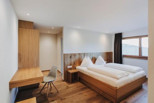 1 dormitorio con cama, escritorio y silla en Familienhotel Lagant, en Brand