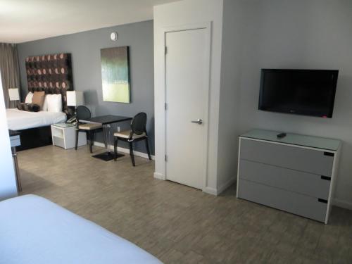 a hotel room with a bedroom with a bed and a television at Lotus Boutique Inn and Suites in Ormond Beach