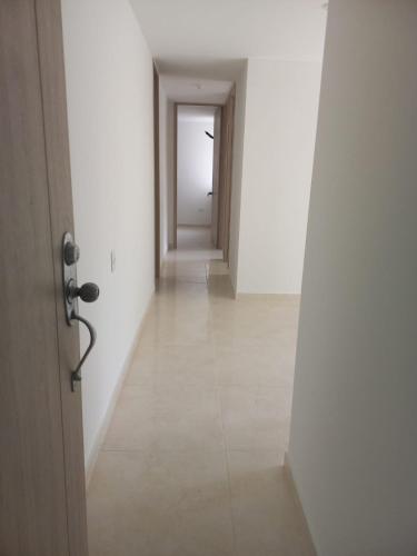 un pasillo vacío con una puerta y un pasillo con paredes blancas en vendo apartamento en el barrio Rosario, en Barranquilla