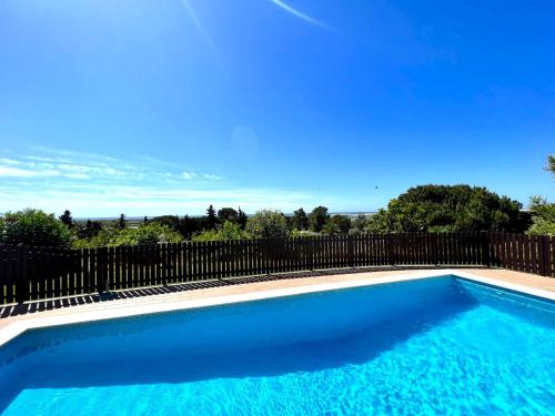 a blue swimming pool next to a fence at Tavira Vila Formosa 5 With Pool by Homing in Tavira