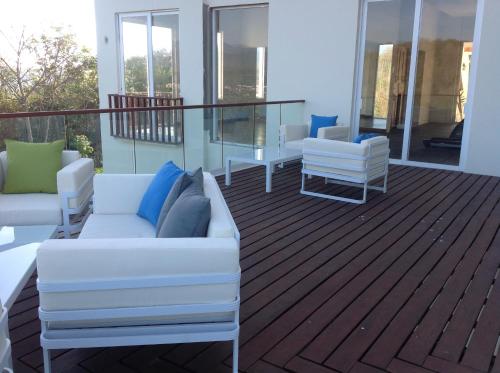 a balcony with white couches and chairs on a deck at Mansiones Cruz del Mar Huatulco in Santa Cruz Huatulco
