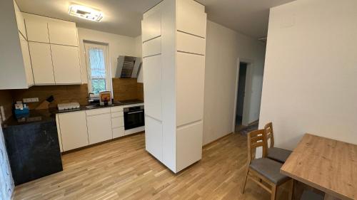 a kitchen with white cabinets and a table in a room at Himmelblau by Strandclub Velden in Velden am Wörthersee