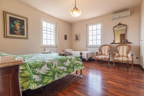 1 dormitorio con 1 cama, 2 sillas y espejo en Italian Experience-Glicine Holiday Apartment, en Castello Ripalta