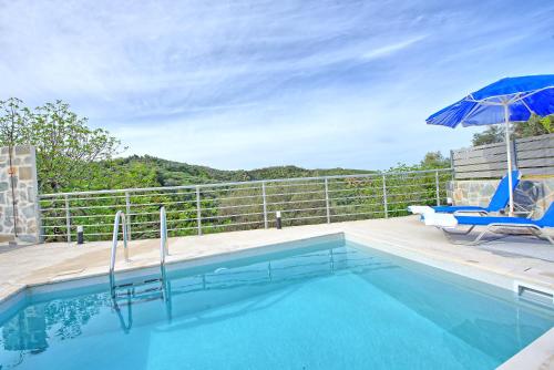 a swimming pool with a blue umbrella and a chair and an umbrella at Aretousa by PosarelliVillas in Dhrakóna
