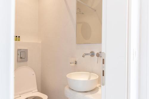 a white bathroom with a sink and a toilet at Asimina Hotel in Fira
