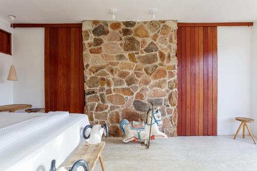 Habitación con pared de piedra, cama y banco. en Toca do Frei - Ilha do Ferro, en Pão de Açúcar