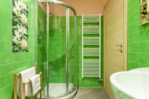 uma casa de banho com azulejos verdes, um chuveiro e um lavatório. em Malpensa Garden em Case Nuove