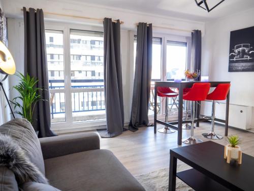 - un salon avec un canapé et une table avec des chaises rouges dans l'établissement Le Nancy gare Hypercentre, à Nancy