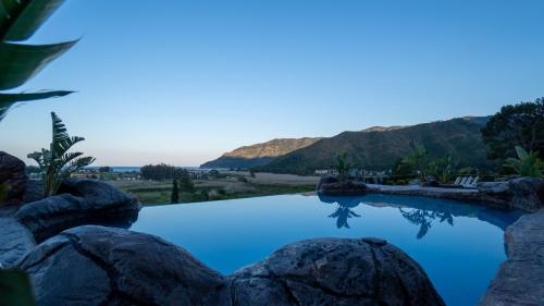 a swimming pool with rocks and mountains in the background at Adrasan Kayaköy Villaları in Kumluca