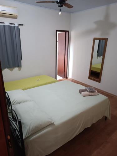 a bedroom with a large white bed and a mirror at Casa Ana in Dourados