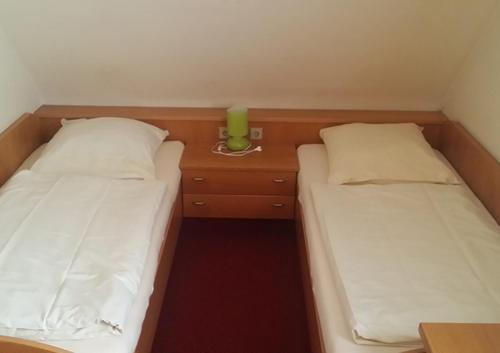 two twin beds in a small room with a night stand at Schwäbischer Hof in Markgröningen