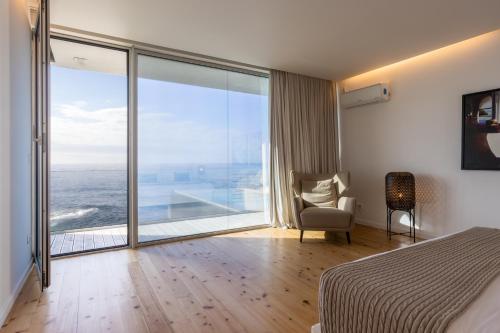 een slaapkamer met een bed en uitzicht op de oceaan bij Casa da Rocha by White Exclusive Suites & Villas in Lagoa