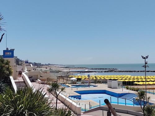 un complejo con piscina y playa con sombrillas en Hostel El Rejunte en Mar del Plata