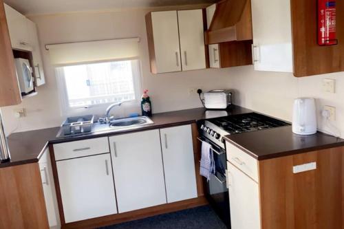 a small kitchen with a stove and a sink at Whitley bay caravan retreat in Whitley Bay