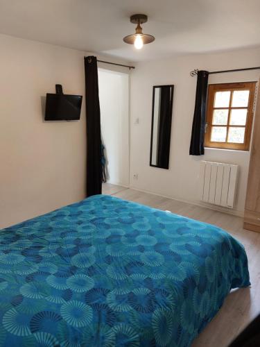 uma grande cama azul num quarto com uma janela em La Champêtre em Beaumesnil