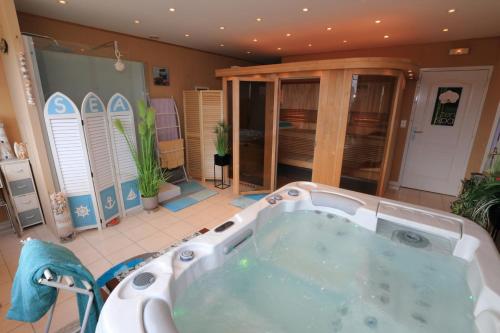 Gîte Le DANON في Trelou Sur Marne: حوض استحمام كبير في غرفة مع ألواح ركوب الأمواج