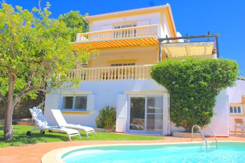 a villa with a swimming pool in front of a house at Villa Flores in Carvoeiro