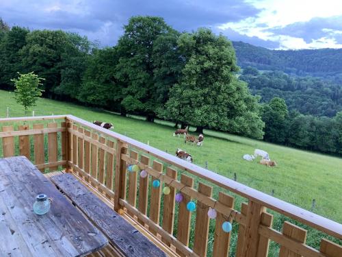 a wooden deck with a table and cows in a field at Maison chaleureuse à Vaucluse avec jardin spacieux 84 m² in Vaucluse