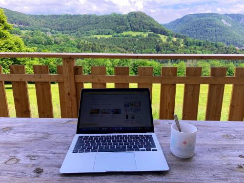a laptop computer sitting on a wooden table with a cup at Maison chaleureuse à Vaucluse avec jardin spacieux 84 m² in Vaucluse