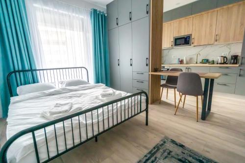 a bedroom with a bed and a table and a kitchen at Your New and Modern Home in Bucharest