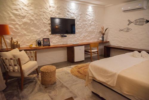a bedroom with a bed and a desk with a television at Moriá Eco Lodge in Icaraí